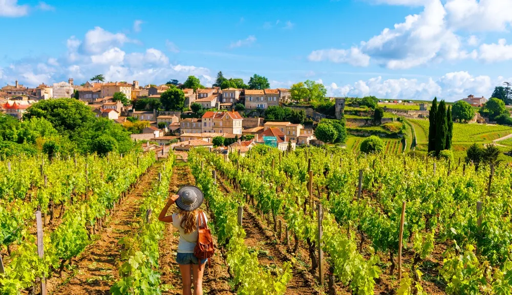 Femme dans le vignoble de Saint-Émilion avec le village au fond.