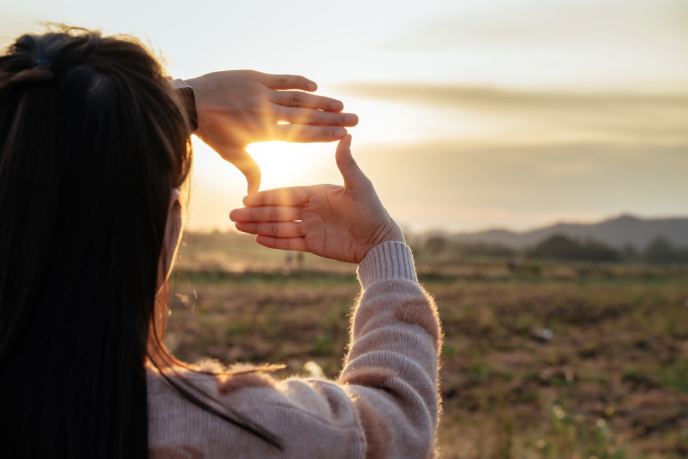 femme regardant un coucher de soleil à la campagne