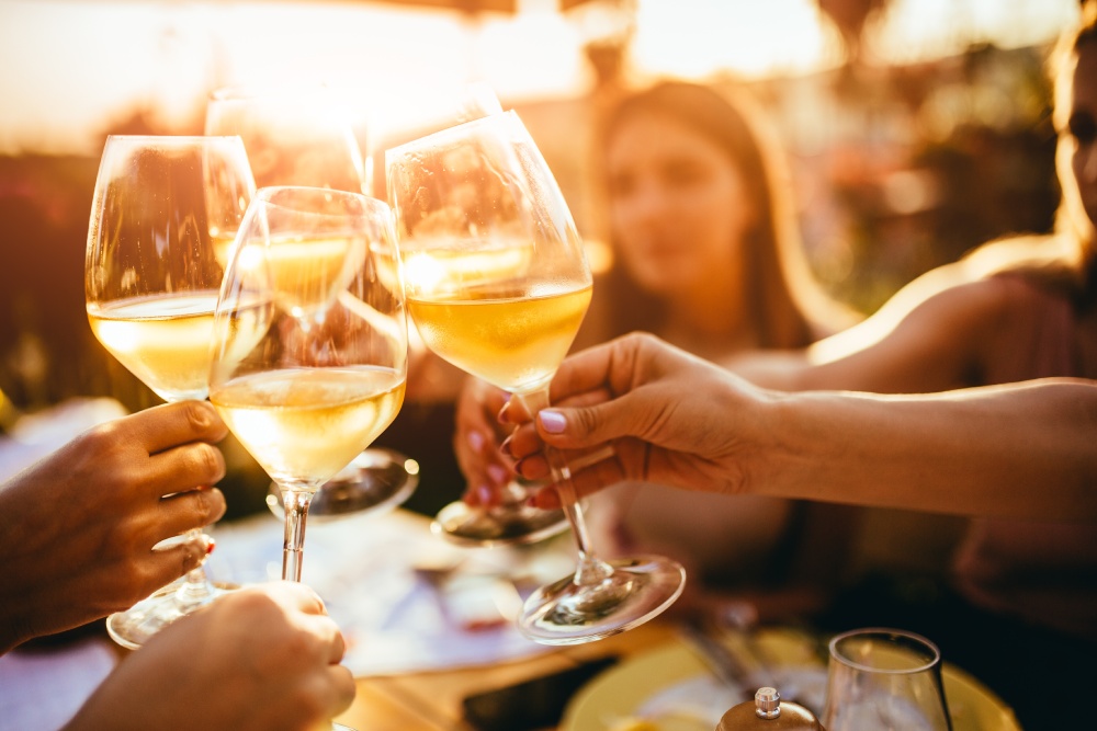 personnes qui trinquent avec des verres de vin blanc