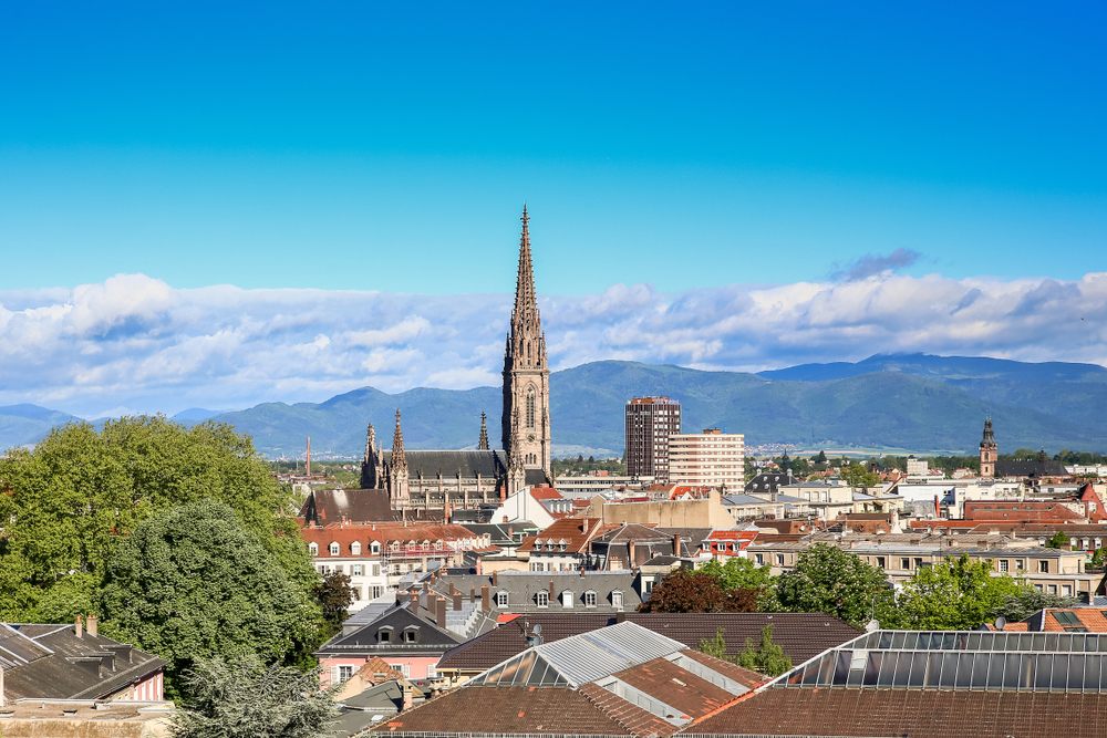 vue de mulhouse avec cathédrale et montagnes au fond