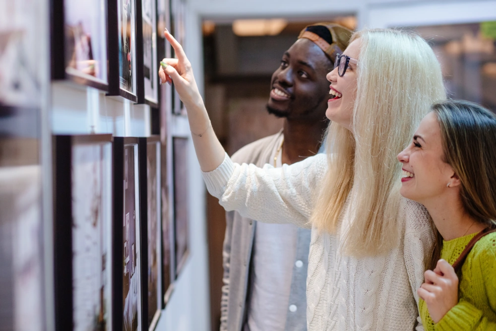 trois personnes, un homme et deux femmes, regardent une exposition de photos dans un tiers-lieu.