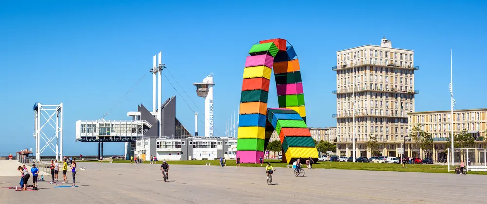 La plage du HAvre et les bâtiments classés par l'Unesco avec une oeuvre d'art en conteneurs colorés.