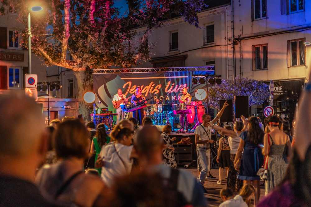 Concert sur La place du marché de Roanne avec du public qui danse devant la scène.